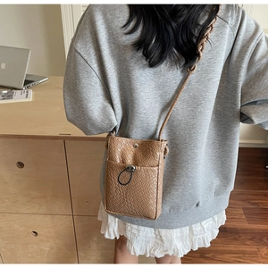Brown crocodile texture mini crossbody phone bag shown on a model in a minimal setting