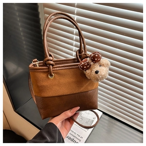 Close-up of vintage brown bucket bag with plush bear charm and leather handles