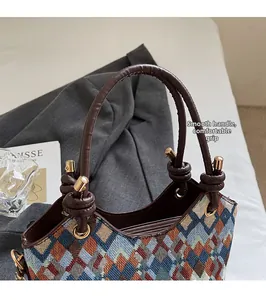 Detail of round leather handle and zip closure on geometric woven bucket bag