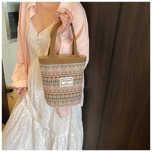 Gros plan d'un sac à main tissé rétro avec motifs ethniques et anses marron robustes