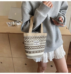 Detail of canvas bucket bag with retro geometric patterns on wooden desk with laptop