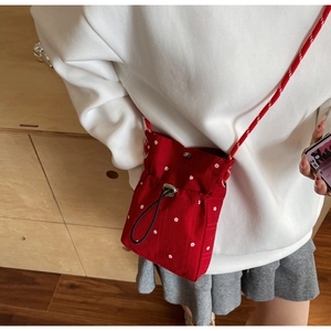 Close-up of red floral crossbody mini bag with white flower patterns and drawstring