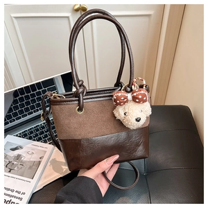 Detail of vintage bucket bag featuring brown leather patchwork and teddy bear charm