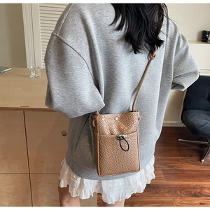 Detailed view of woven brown crossbody phone bag with drawstring closure on model