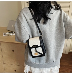 Chic black and white mini crossbody bag with crocodile texture shown in home setting