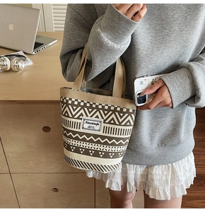 Detailed shot of ethnic pattern canvas mini tote bag with branding tag on a wooden desk