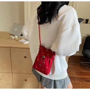 Detail view of red floral drawstring bucket bag with white flowers and woven strap