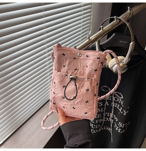Detail of pink quilted nylon phone bag with bow patterns and woven rope strap