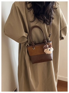 Detail of vintage bucket bag featuring contrast brown textures and a cute puppy charm