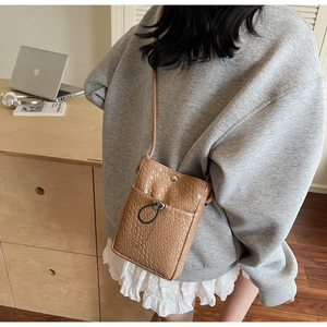 Detail of caramel crocodile pattern synthetic leather phone bag with silver buckle