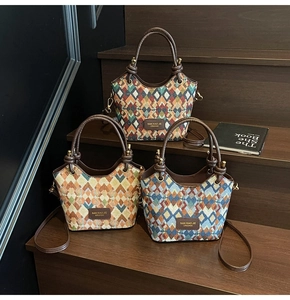 Detailed view of three bohemian rhombic bucket bags with leather handles on wooden stairs