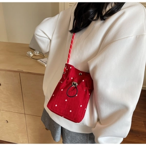 Detail of red floral drawstring bucket bag with sports-style woven nylon strap