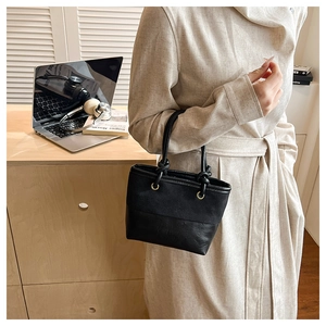 Detail of minimalist black leather and canvas bucket bag with a unique knot handle