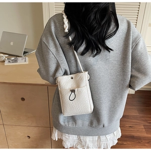 Detail of white woven mini crossbody bag with knotted rope strap and metal buckle closure