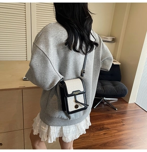Detail of woven crossbody bag showing textured white fabric and black leather trim