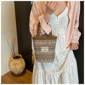Gros plan d'un sac seau bohème tissé multicolore porté par un mannequin en intérieur
