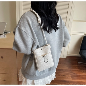 Detail view of cream woven crossbody phone bag with chunky strap on model