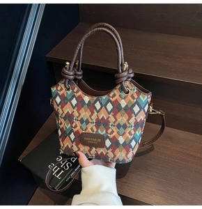 Macro detail of geometric quilted bucket bag with colorful woven pattern and leather strap