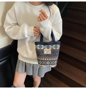 Ethnic style canvas bucket bag with elephant pattern and blue handle on wooden stairs
