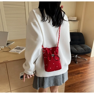 Close-up of red floral drawstring crossbody bag with white flower patterns and rope strap