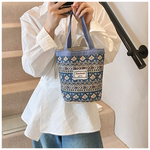 Détail du sac seau en toile bleue avec motifs géométriques et étiquette blanche