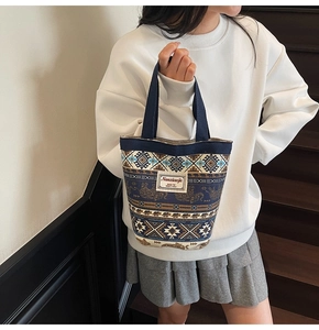 Detailed close-up of ethnic canvas tote bag with elephant patterns and woven handles