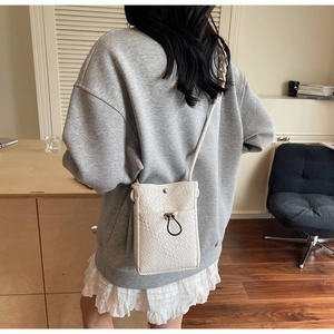 Close-up of white crocodile pattern phone crossbody bag shown on a model's outfit