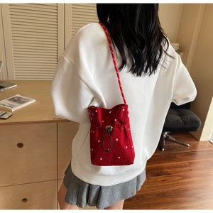 Detail of red floral canvas mini bag with drawstring closure and woven shoulder strap