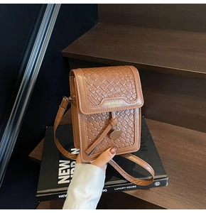 Detail of brown woven faux leather mini crossbody bag with logo and adjustable strap