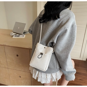 Detailed view of white crocodile pattern cross-body phone bag worn with casual outfit