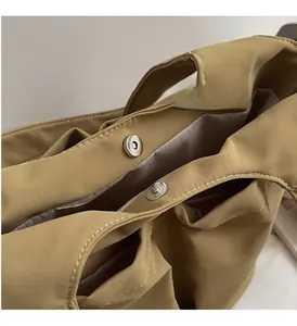Dettaglio della fibbia magnetica argentata e tessuto kaki cangiante con cuciture precise