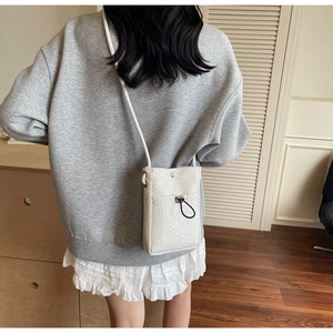 White woven crossbody phone bag detail with black drawstring buckle shown on model