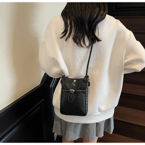 Detail of black woven crossbody phone bag showing high-quality synthetic leather texture