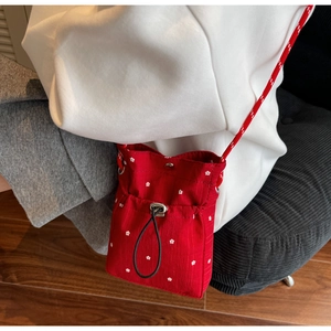Detail of red floral crossbody bag featuring drawstring closure and textured fabric