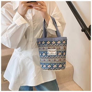 Détail d'un sac seau bohème avec des motifs géométriques tissés colorés et des poignées