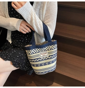 Ethnic geometric canvas bucket bag with blue patterns shown in a lifestyle outdoor setting