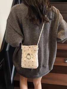 Quilted white crossbody bag with black bird print and drawstring in a lifestyle setting