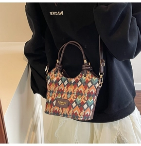 Detail of colorful geometric quilted bucket bag with brown leather trim and metal hooks