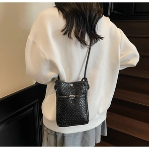 Detail of woven texture and silver metal twist lock on black leather phone crossbody bag