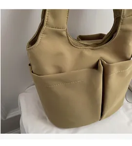 Dettaglio della borsa tote kaki con tasche esterne multiple e cuciture bianche a contrasto