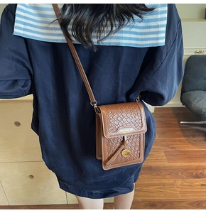 Brown woven leather shoulder bag with tassels shown on a model's back in a modern room