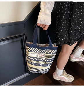 Close-up of geometric pattern canvas bucket bag held while walking on wooden stairs