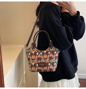 Detail of colorful geometric diamond pattern weave and brown leather handles on bucket bag
