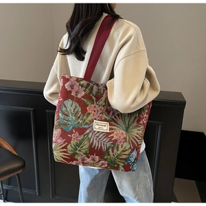 Detail of red floral jacquard tote bag featuring green palm leaves and red woven straps