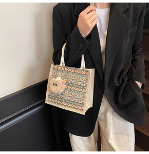 Close-up of geometric patterned ethnic tote bag with plush charm and braided handles