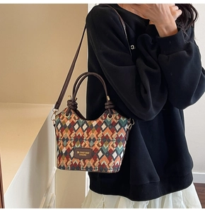 Detail of colorful geometric quilted jacquard pattern and leather logo patch on bucket bag