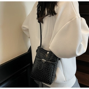 Detail of black woven texture phone bag with silver buckle and braided shoulder strap