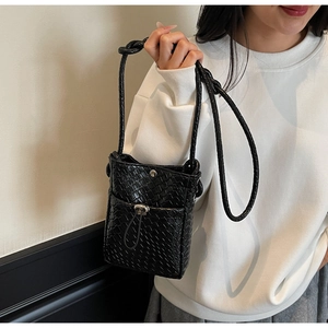 Close-up of black woven texture phone bag with silver metallic turn-lock and crossbody strap