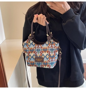 Detail of multicolored woven diamond pattern bucket bag with leather handles and strap