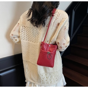 Detailed texture of red woven leather crossbody phone bag with snap closure and drawstring